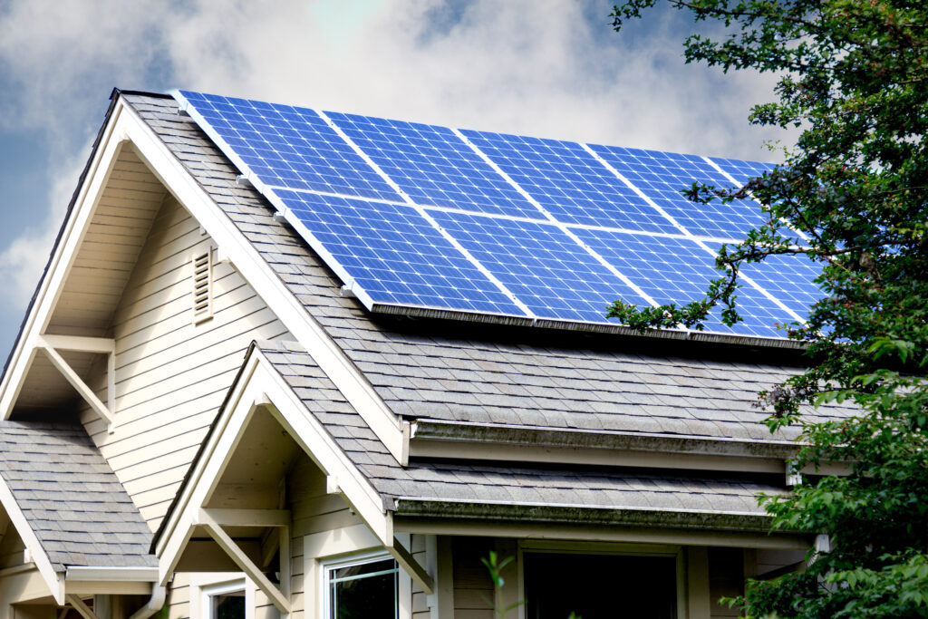 A home with a gray shingle roof with many solar panels.