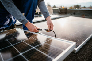 A faceless man connects a solar panel.